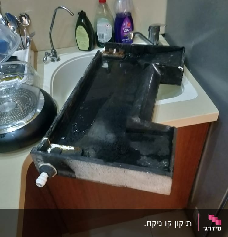 מגש ניקוז של מזגן מונח על כיור במטבח